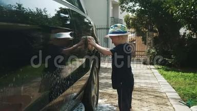 戴帽子的小男孩用肥皂和海绵洗一辆车